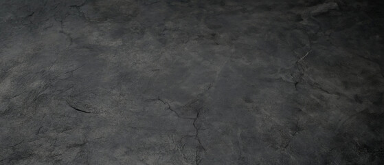 Fototapeta premium Close-up of a dark, textured stone surface with visible cracks and natural imperfections, ideal for backgrounds or design use.