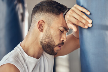 Fototapeta premium Tired man, boxer and rest with punching bag for self defense training, practice or martial arts at gym. Exhausted male person or fighter in fitness for break after intense exercise or boxing match