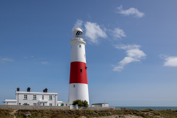 The iconic lighthouse at Portland Bill in Dorset, United Kingdom. Taken with a blue sky and light cloud. there is space for copy text and there are no people