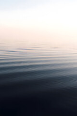 Fototapeta premium A serene view of calm water with gentle ripples, reflecting a soft blue hue. The surface appears smooth and tranquil, creating a peaceful atmosphere.