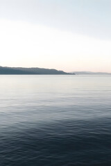 Fototapeta premium A serene view of calm water with gentle ripples, reflecting a soft blue hue. The surface appears smooth and tranquil, creating a peaceful atmosphere.