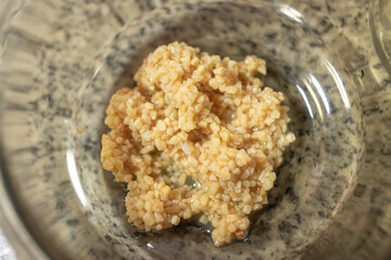 Chopped garlic in a glass bowl along with other ingredients needed to prepare chiles en nogada