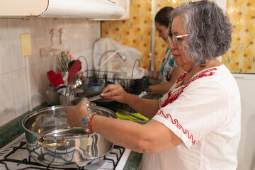 Women dressed in traditional Mexican clothing preparing the ground beef filling needed to prepare...