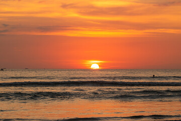 Vibrant Ocean Sunset. A stunning sunset over the ocean with vibrant orange and yellow hues casting a warm glow across the water as the sun dips below the horizon. yellow clouds in red sky background