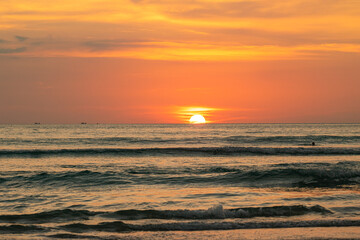 Vibrant Ocean Sunset. A stunning sunset over the ocean with vibrant orange and yellow hues casting a warm glow across the water as the sun dips below the horizon. yellow clouds in red sky background