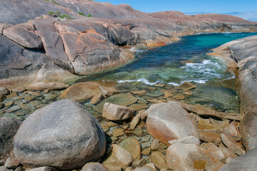 Elephant Rocks in Western Australia, where massive granite boulders meet crystal-clear turquoise waters, creating a serene coastal landscape under a bright blue sky. A stunning natural attraction.