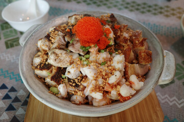 Rice bowl dish featuring a delicious combination of tender seafood, including shrimp, topped with bright orange fish roe and a sprinkling of crispy fried garlic. 