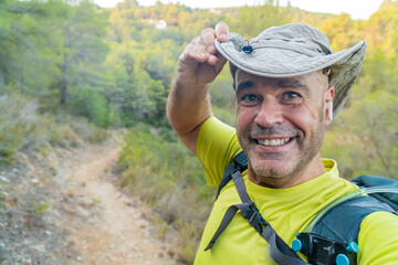  Smiling middle aged hiker taking a selfie outdoors