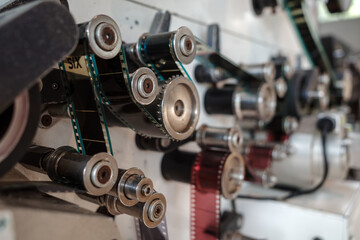 A detailed close-up view of a vintage film projector&rsquo;s mechanical components, showcasing gears, rollers, and belts.