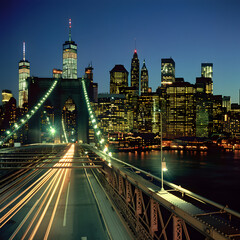 Obraz premium Long exposure of cars driving across the brooklyn bridge at twilight with the illuminated skyline of lower manhattan in the background