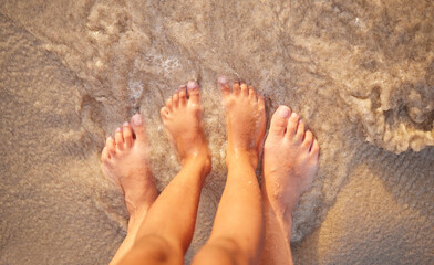 Feet, sand and water with couple on beach together for holiday, travel or vacation from above. Date, romance or security with people on coast of tropical island paradise in ocean or sea closeup