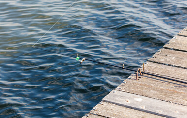 A fisherman's fishing rod on a wooden bridge on a lake