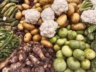 Fresh organic vegetables displayed at local market, assorted vegetable produce greens, taro root cauliflower, potatoes, apple gourd, agriculture produce mixed veggies vegetarian food at market 