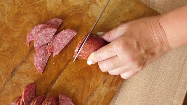 Cut salami for cooking. Cooking homemade meals.