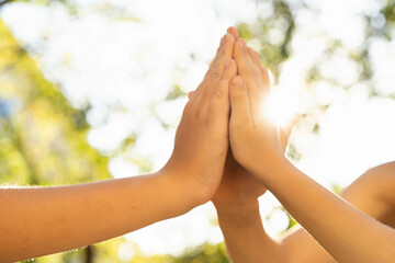 children holding hands, standing on the green grass, the concept of friendship and a group of young people working in a team, side view