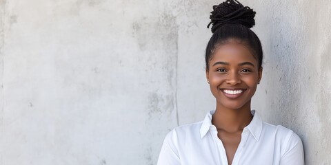 A smart young smiling black businesswoman standing in front of a white weathered concrete wall