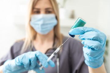 Biological hazard. Epidemic of the Chinese coronavirus. An woman in a protective mask holds an injection syringe and vaccine. Vaccine flu, coronavirus, ebola, TB.