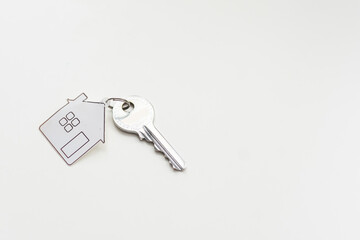 Key with house shape keychain on grey background
