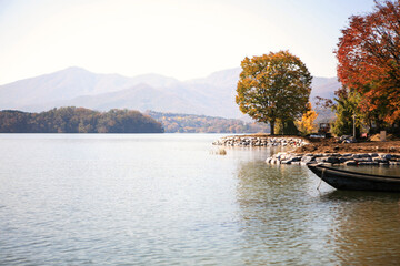 Fototapeta premium tranquil landscape at the lakeside with a wooden boat in autumn