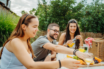 Group of three friends or family having picnic in backyard or garden