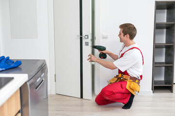 Drilling and installation of interior doors, the craftsman makes a hole in the door frame with a hand drill, doors and installation.
