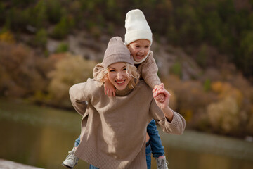 A beautiful young mother with kid spends time with her child outdoors together against the backdrop...
