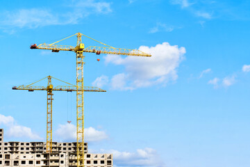 Yellow Construction Cranes Erected Above Urban Building