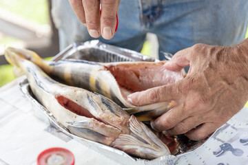 A man is preparing fish on a table
