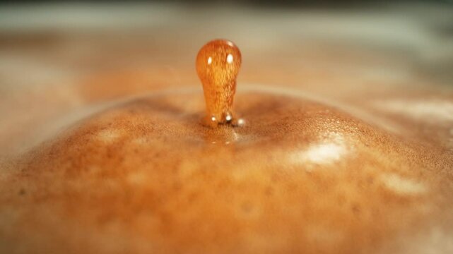 Super Slow Motion Shot of Perfect Drop Falling into Fresh Creamy Coffee at 1000fps.