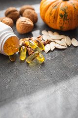 Yellow capsules of omega 3, fatty acid supplement pills with pumpkin seeds and walnuts