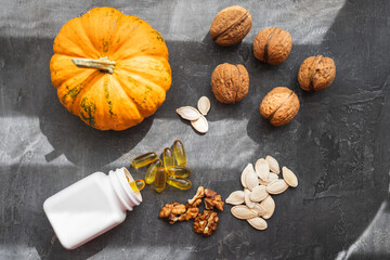 Yellow capsules of omega 3, fatty acid supplement pills with pumpkin seeds and walnuts