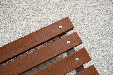 Garden bench diagonally against the background of the wall, old wooden board