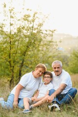Fototapeta premium Grandparents and grandson together in autumn park