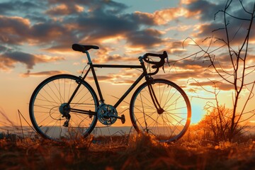 Fototapeta premium A single bike parked in a field with the setting sun in the background