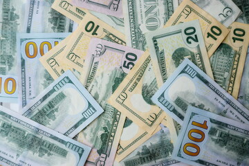 Big amount of US dollar bills in different nominations on table. Many dollar banknotes under natural light