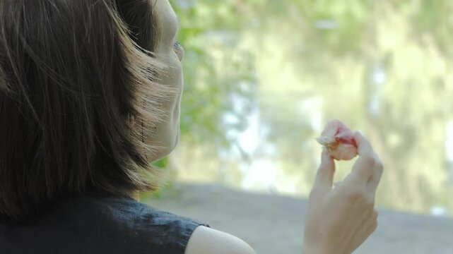 A woman eats a fig peach in a park during a picnic