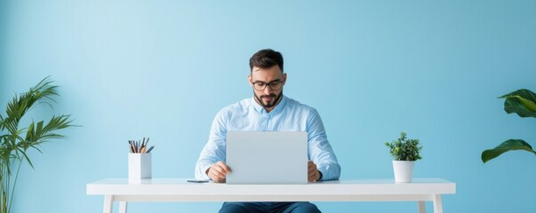 A focused man working on a laptop at a stylish desk, surrounded by greenery, ideal for modern work concepts and productivity themes.