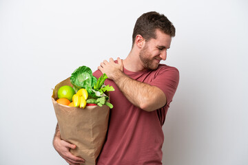 Young caucasian man holding a grocery shopping bag isolated on white background suffering from pain in shoulder for having made an effort