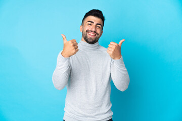 Caucasian man over isolated blue background with thumbs up gesture and smiling