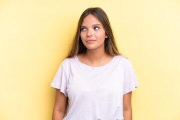 Fototapeta premium Young caucasian woman isolated on yellow background making doubts gesture looking side