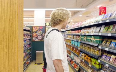 Young man shopping in supermarket, reading product information