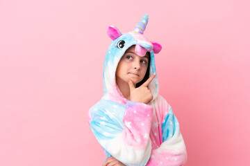 Little caucasian woman wearing a unicorn pajama isolated on pink background happy and smiling