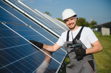 Man technician mounting photovoltaic solar moduls. Engineer in helmet installing solar panel system outdoors