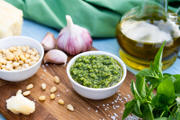 ingredients for the preparation of pesto sauce. basil, pine nuts, garlic, basil, parmesan on a blue table and wooden board