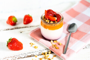 Fruit yogurt berry with muesli and fresh strawberries, on a white wooden background