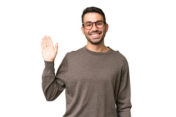 Young handsome caucasian man over isolated background saluting with hand with happy expression © luismolinero