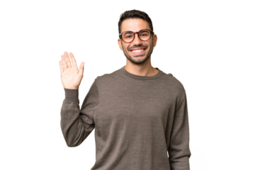 Young handsome caucasian man over isolated background saluting with hand with happy expression