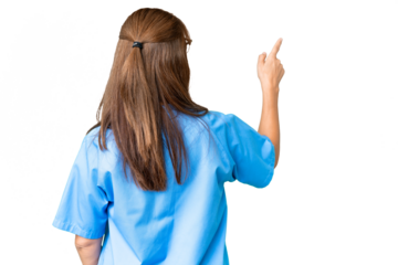 Middle age nurse woman over isolated background pointing back with the index finger