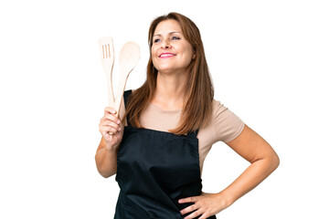 Middle age caucasian woman holding a rolling pin over isolated background posing with arms at hip and smiling