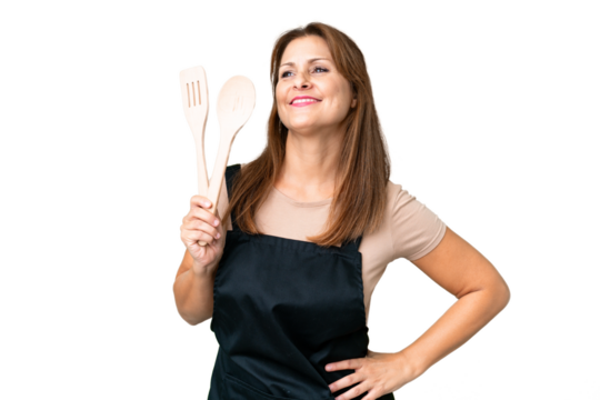Middle age caucasian woman holding a rolling pin over isolated background posing with arms at hip and smiling